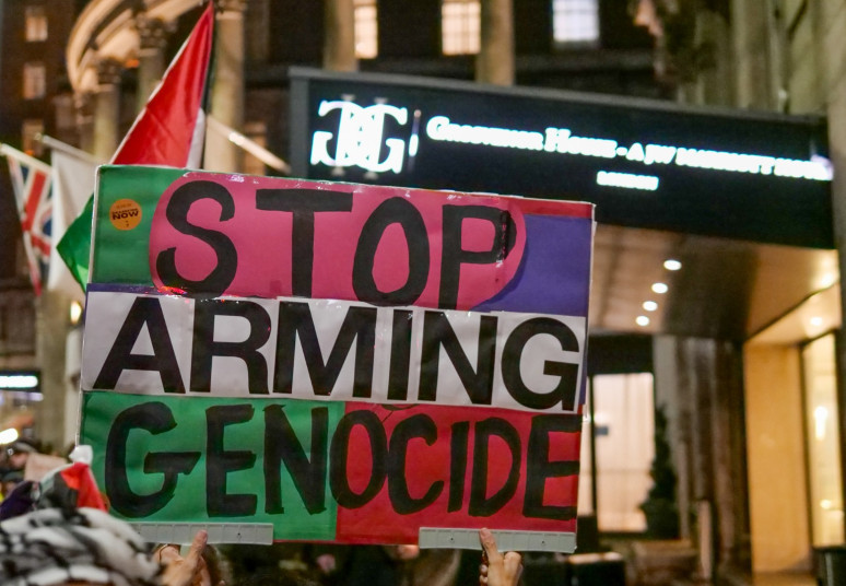 A placard reading STOP ARMING GENOCIDE