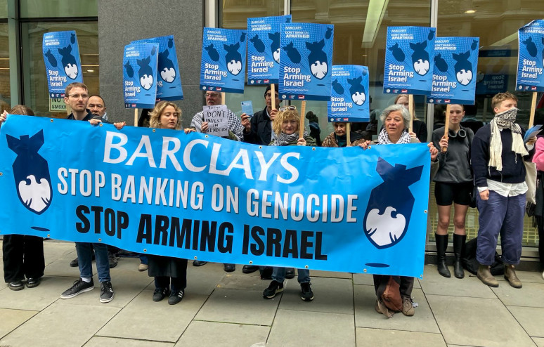 Banner being held outside Barclays stating "Stop Banking On Genocide - Stop Arming Israel"