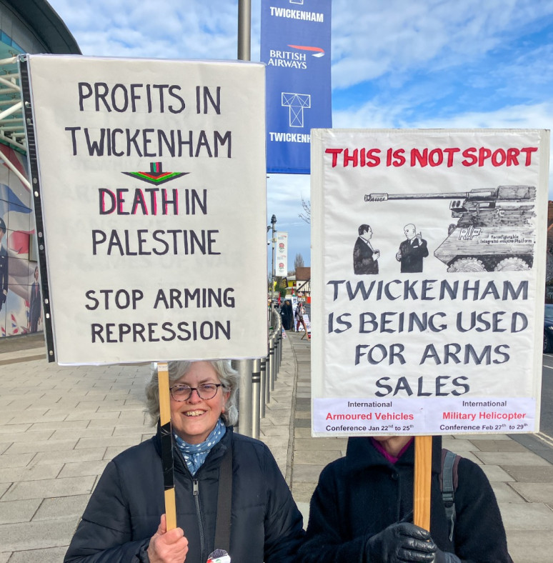 2 protesters holding placards opppsing Twickenham being used to sell weapons