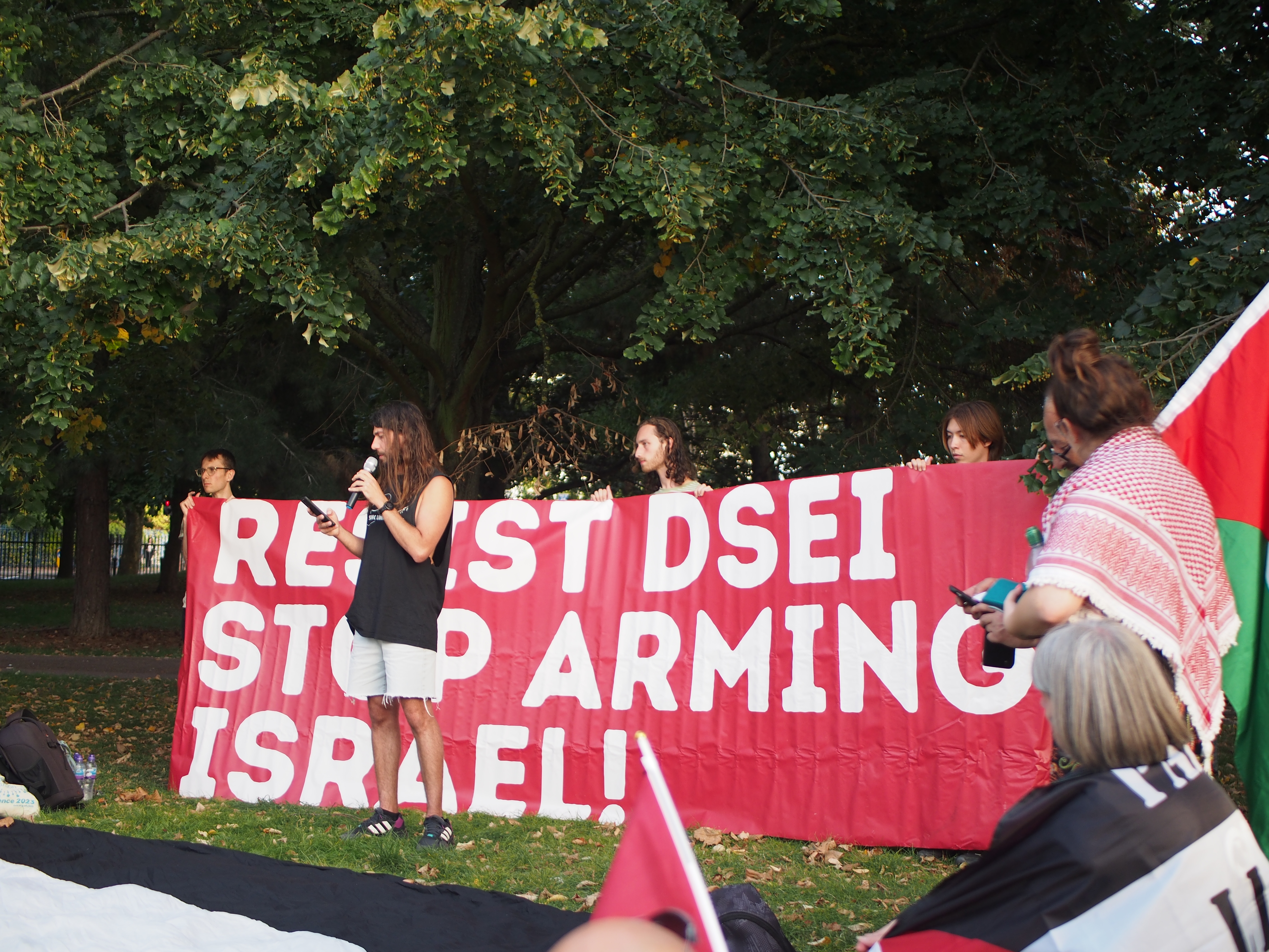 Protesters in front of a banner with the words "Resist DSEI, Stop Arming Israel"