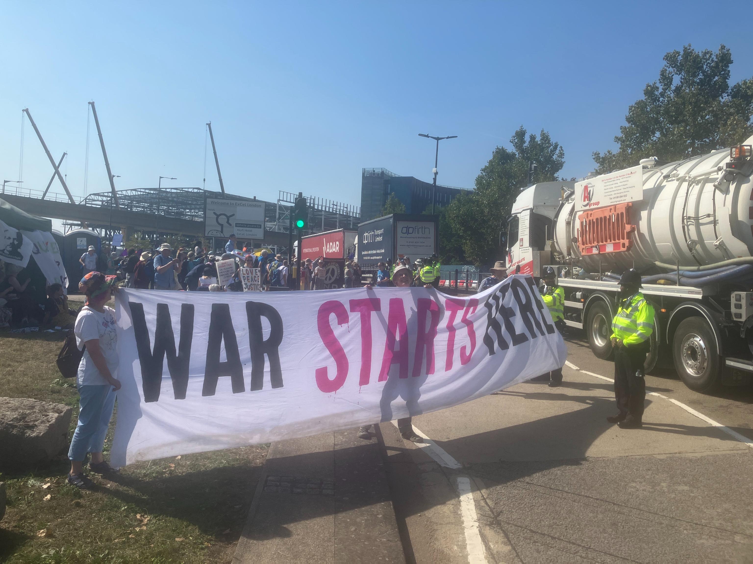 Protesters blocking arms trade truck with a war starts here banner